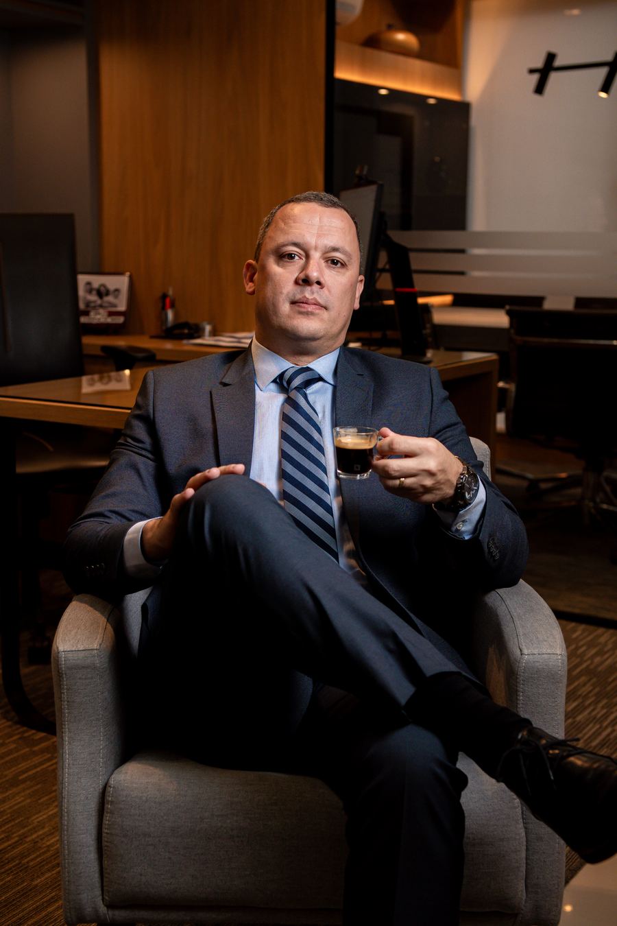 Ivandro Noronha de Freitas sentado numa poltrona, com uma xícara de café